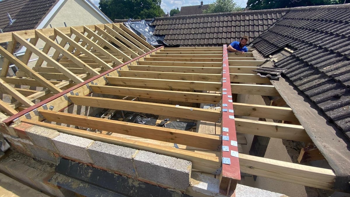Roof framing construction showing wooden joists and beams being installed on a house renovation project