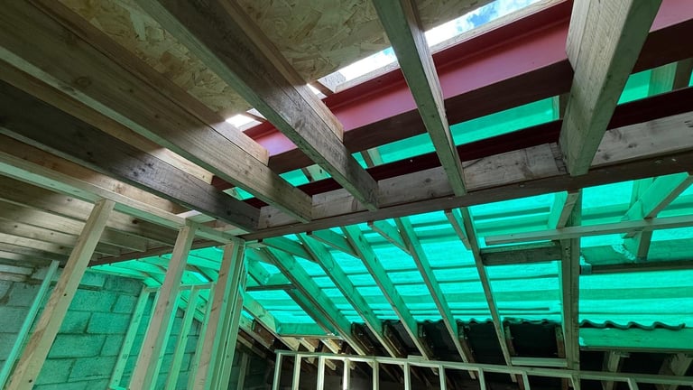 Construction interior with concrete beams and structural framework, bright turquoise and green skylights overhead